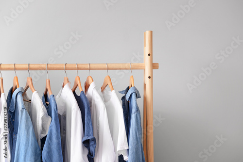 Rack with hanging clothes on light background photo