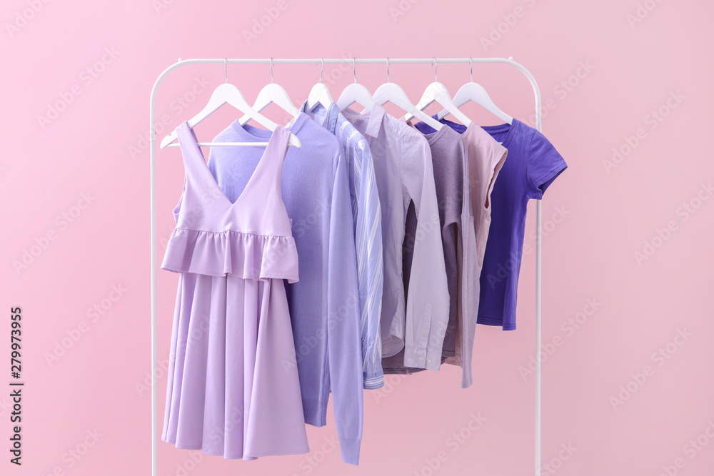 Rack with hanging clothes on color background Rack with hanging clothes on color background