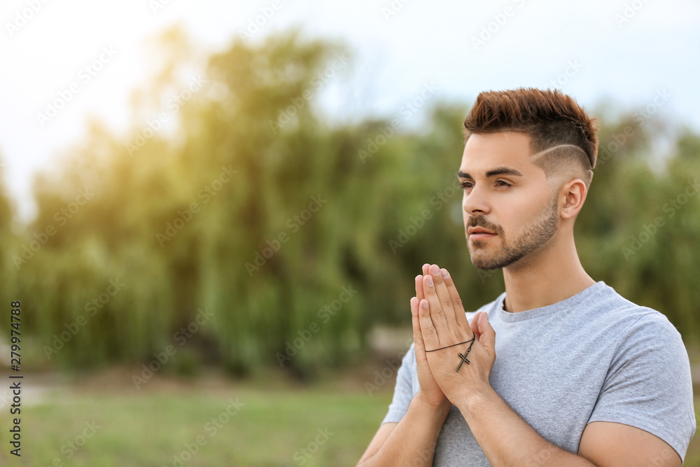 Fototapeta premium Young man praying to God outdoors