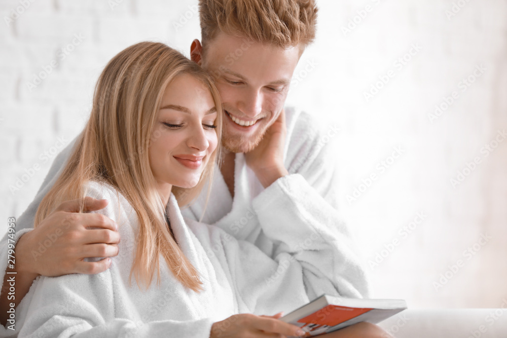 Happy young couple in bathrobes reading magazine at home Happy young couple in bathrobes reading magazine at home