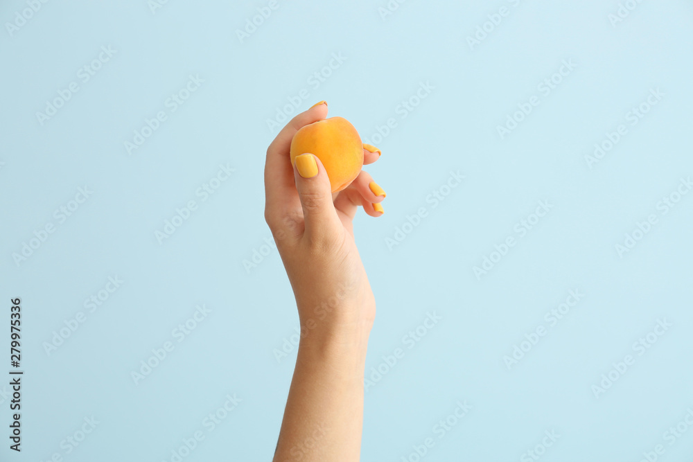 Female hand with tasty apricot on light background Female hand with tasty apricot on light background