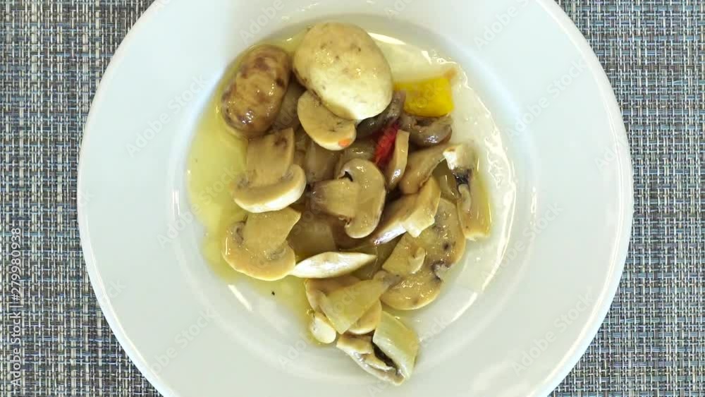 Mushrooms with sauce on a rotating plate. View from above. A plate of food is spinning on the table. Mushrooms with sauce on a rotating plate. View from above. A plate of food is spinning on the table.