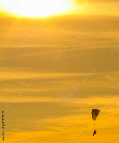 sunset with paragliders pilot flying over clouds