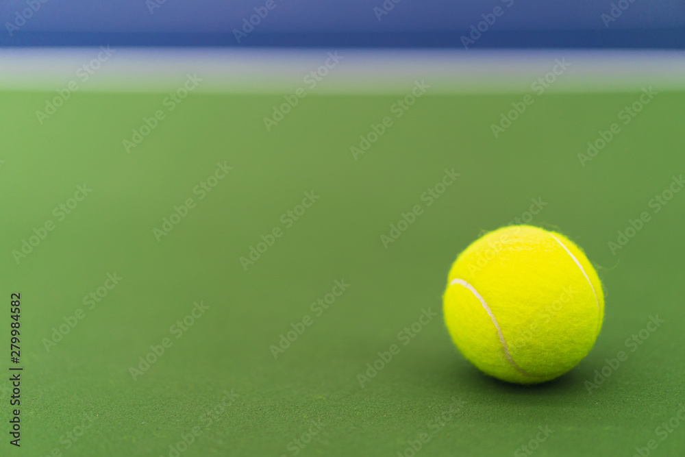 one new tennis ball on blue and green hard court with copy space on left