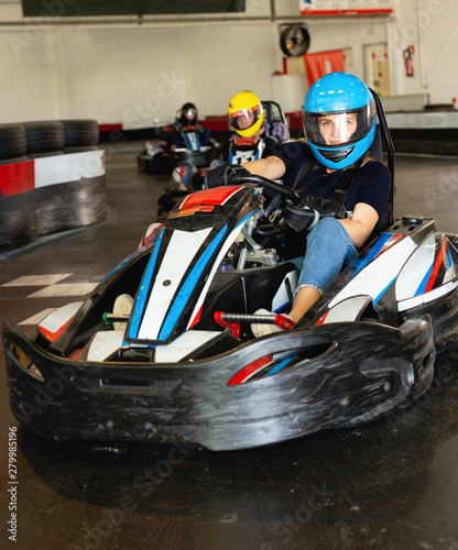 Girl and her friends competing on racing cars at kart circuit