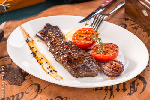 arrachera mexican spiced skirt steak with grilled tomatoes and onion on old map background