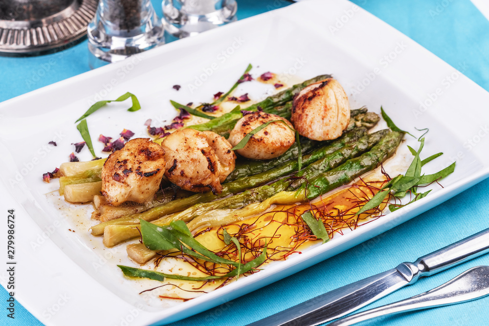 European recipe, Mediterranean dish. Caramelized asparagus with onion chips, rose petals, arugula and pieces of fried fish European recipe, Mediterranean dish. Caramelized asparagus with onion chips, rose petals, arugula and pieces of fried fish