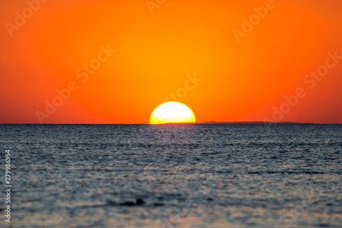 Fototapeta Naklejka Na Ścianę i Meble -  Quiet calm sea against the big setting sun