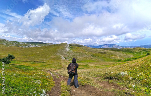 Mountain Chatyr Dag, Crimea. Tourist standing back over beautiful view on mountains and blue sky in summer.