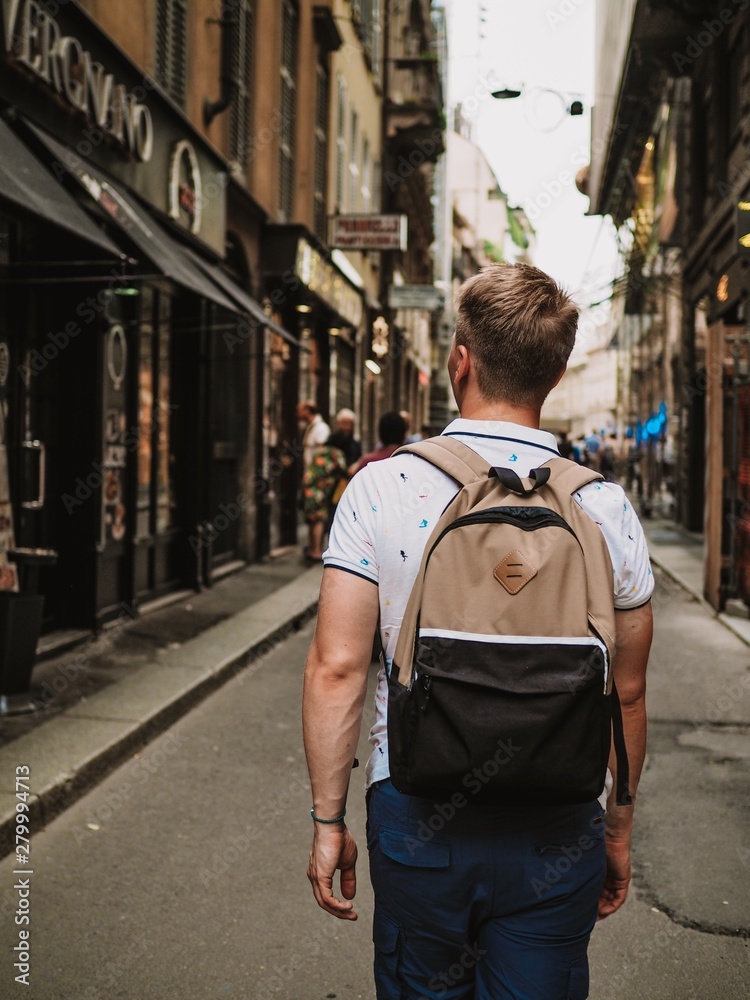 Young blond man with a backpack walking down the street in Milan