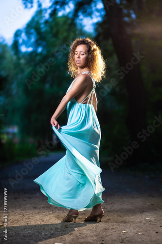 Beautiful fashion model woman dancing in the forest during sunset