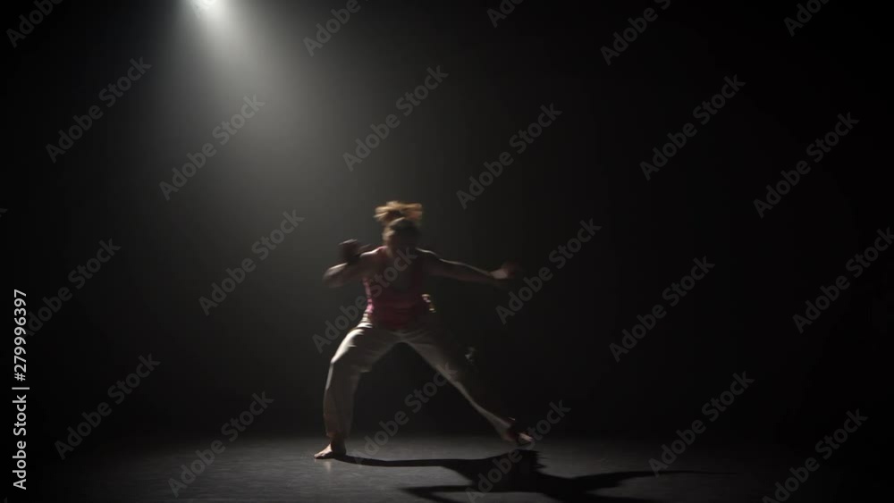 Capoeira in darkness under spotlight at studio Capoeira in darkness under spotlight at studio