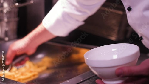 Fries being placed in a bowl and spinkled with salt in slow motion photo