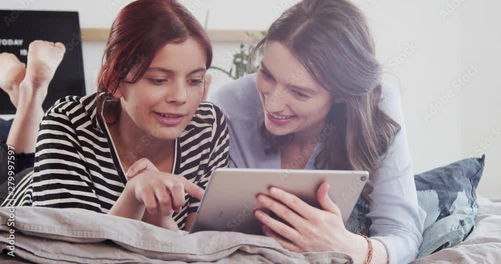 Two friends at home looking at digital tablet Two friends at home looking at digital tablet