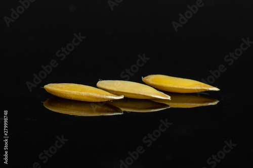 Three seeds of fresh yellow melon canary isolated on black glass photo