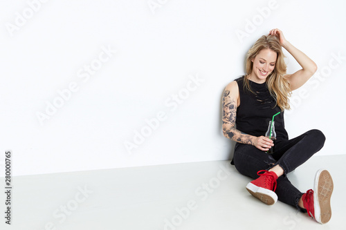 Beautiful young woman holding a bottle of soda on the white background 