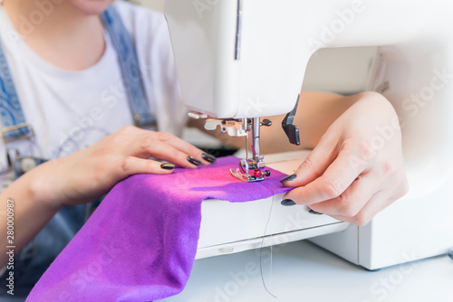 seamstress sits and sews on a sewing machine. The seamstress work on the sewing machine. The tailor makes clothes at his workplace. Hobby sewing as a small business concept. dressmaker