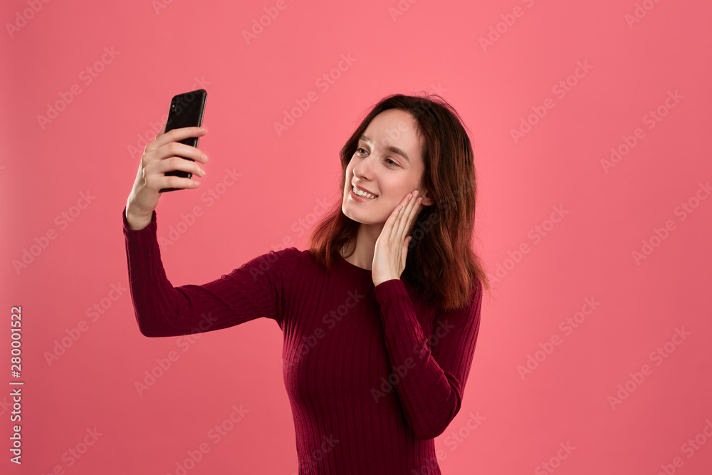 Photo of a pretty young brunette woman making selfie with a mobile phone. Photo of a pretty young brunette woman making selfie with a mobile phone.