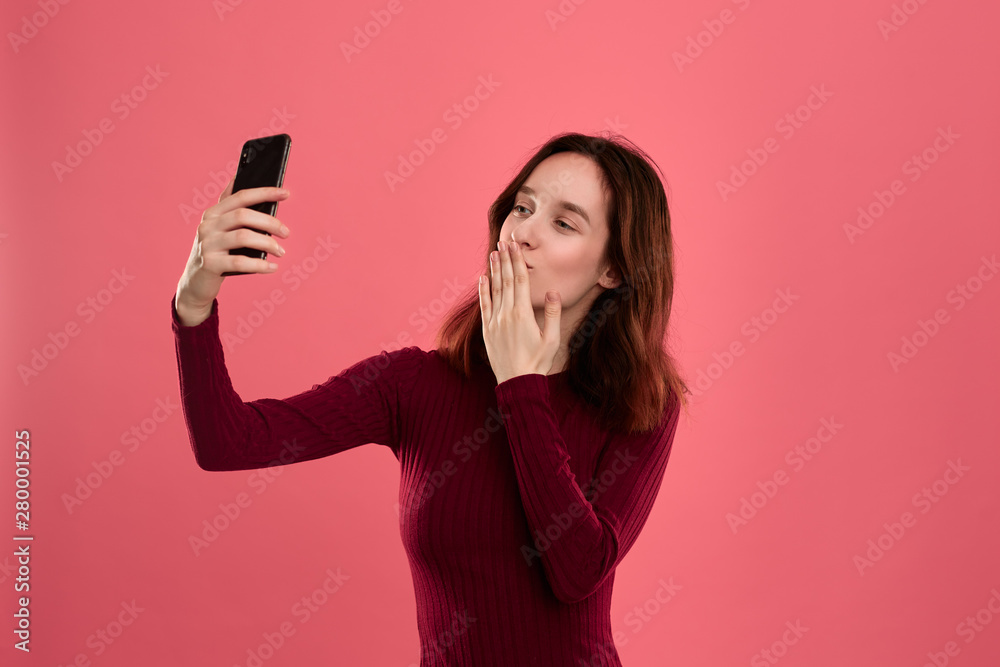 Photo of a pretty young brunette woman making selfie with a mobile phone. Photo of a pretty young brunette woman making selfie with a mobile phone.