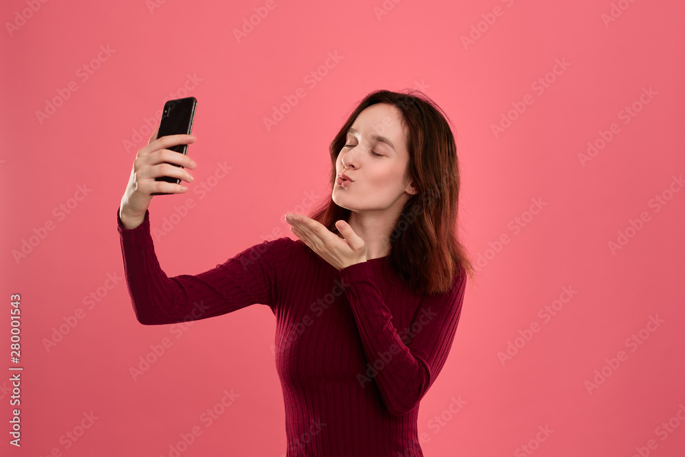 Photo of a pretty young brunette woman making selfie with a mobile phone. Photo of a pretty young brunette woman making selfie with a mobile phone.