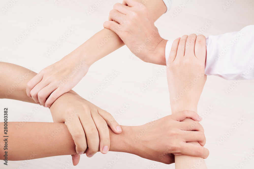 Obraz premium Close-up of young people holding each other for wrist isolated on white background