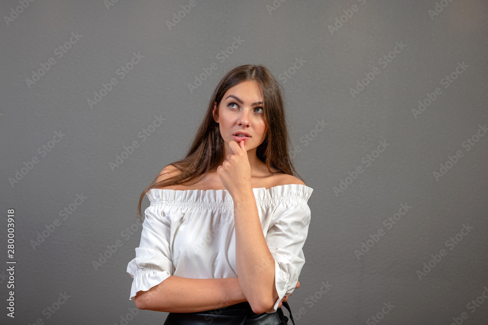 Portrait of a thoughtful woman looking away at copyspace over gray  background - image