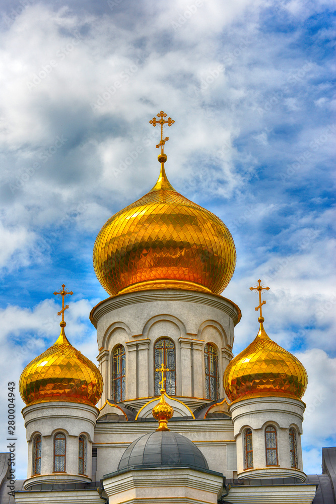 Orthodox Church, golden domes with crosses close-up against a blue cloudy sky, HDR photo.