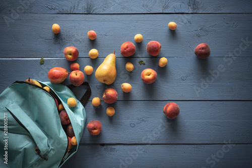 Organic apricots and peaches on blue wooden background, flat lay