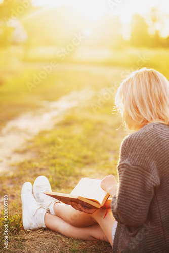 a girl reading a book in a meadow