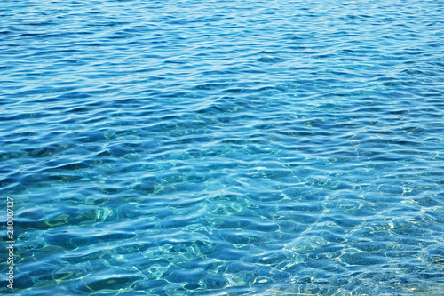 Close up shot of turquoise ocean water with light reflection texture. Tropical background concept. Close up, copy space for text.