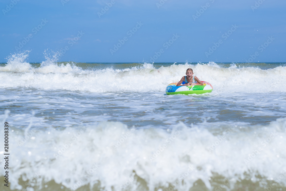 Sea with waves and a girl in an inflatable circle far from the shore. Activities on the beach.