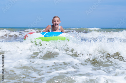 Girl on an inflatable circle in a raging sea, ocean. © Konstiantyn Zapylaie