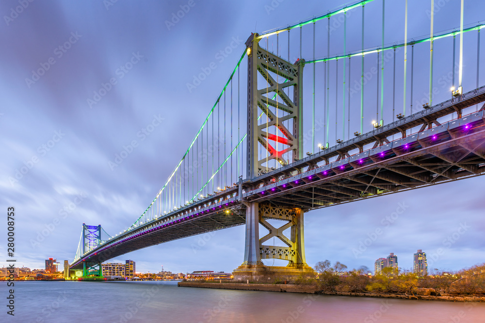 Philadelphia, Pennsylvania, USA skyline on the Delaware river with Ben Franklin Bridge at night.