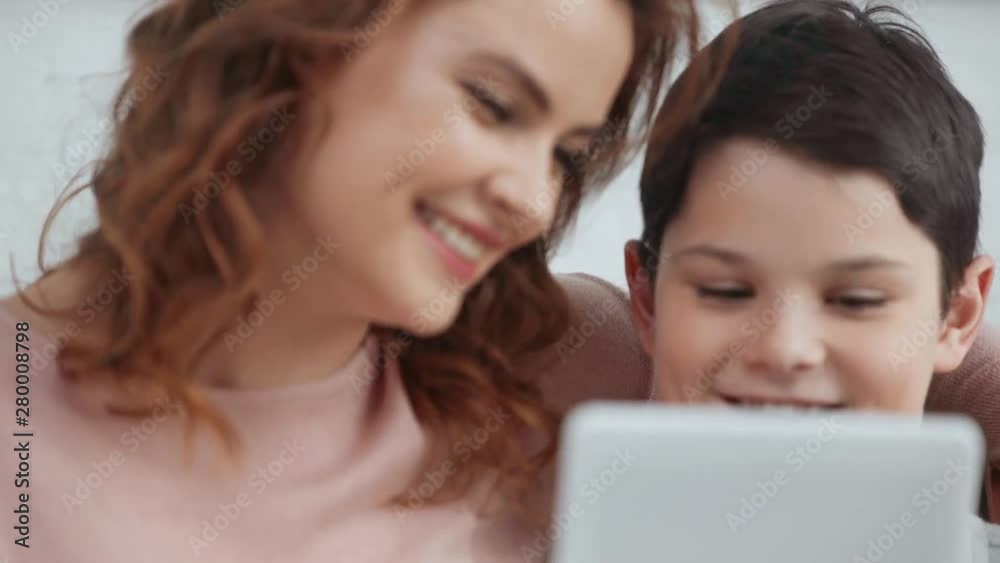 mother and son smiling and using digital tablet together at home mother and son smiling and using digital tablet together at home