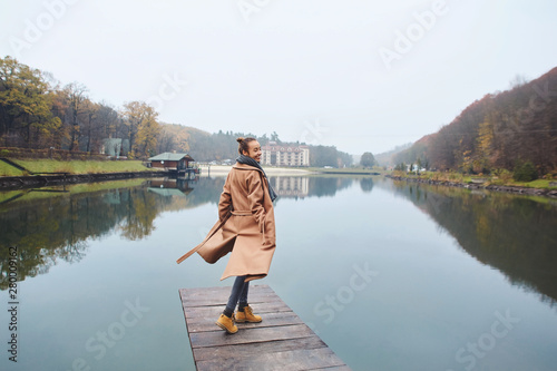 Happy woman walking on the wooden pier in the park at autumn.