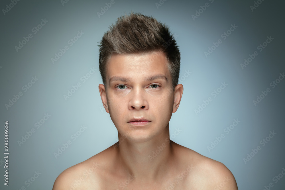 Portrait of shirtless young man isolated on grey studio background. Caucasian healthy male model looking at camera and posing. Concept of men's health and beauty, self-care, body and skin care.