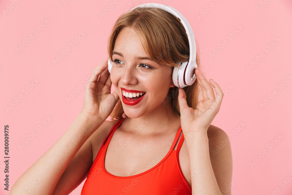 Image of pretty young woman with long curly hair smiling and listening to music with headphones Image of pretty young woman with long curly hair smiling and listening to music with headphones