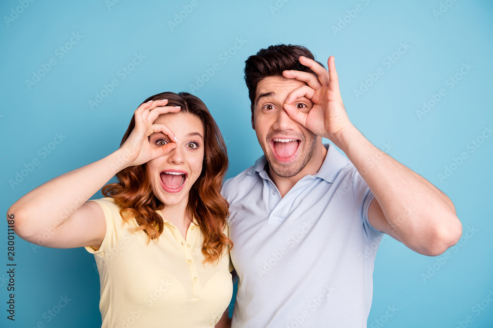 Photo of funky pair excited best buddies okey symbol near eyes specs glasses wear casual t-shirts isolated blue background Photo of funky pair excited best buddies okey symbol near eyes specs glasses wear casual t-shirts isolated blue background