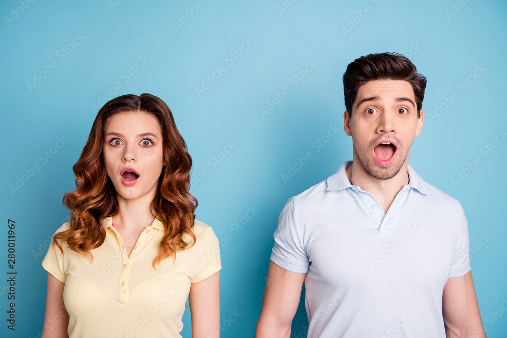 Photo of pair foxy lady brunet guy staring unexpected bad news open mouth wear casual t-shirts isolated blue background Photo of pair foxy lady brunet guy staring unexpected bad news open mouth wear casual t-shirts isolated blue background