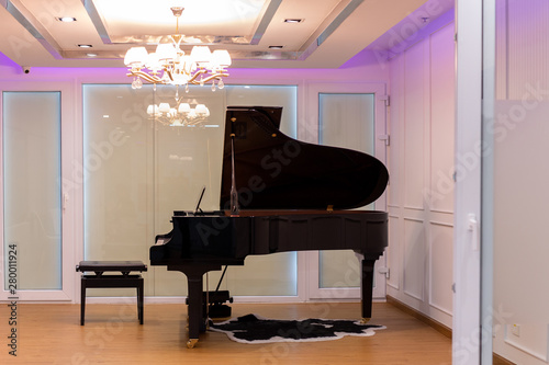 Luxurious music room with grand piano and chandelier with colorful lighting. photo