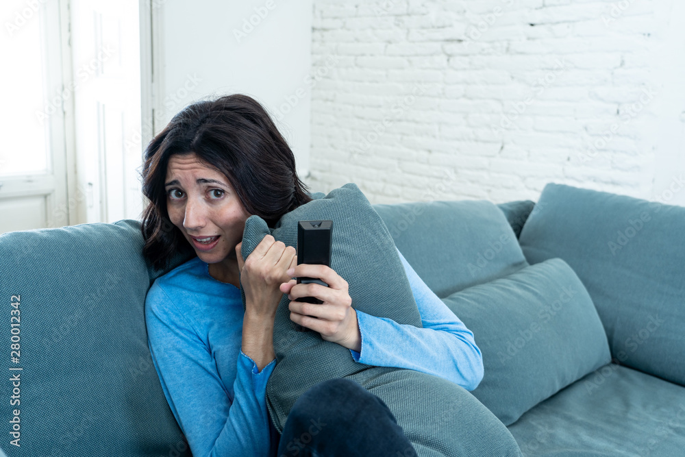 Portrait of a young woman looking scared and shocked watching scary movie on TV. Portrait of a young woman looking scared and shocked watching scary movie on TV.