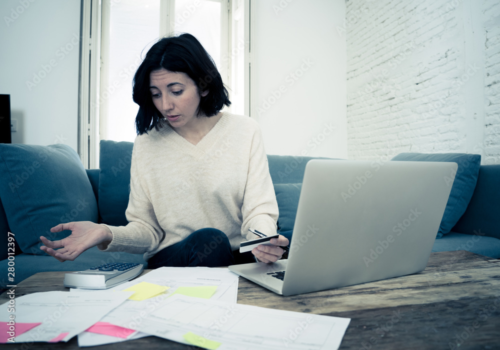 Stressed and overwhelmed young woman trying to manage home finances paying bills feeling desperate Stressed and overwhelmed young woman trying to manage home finances paying bills feeling desperate