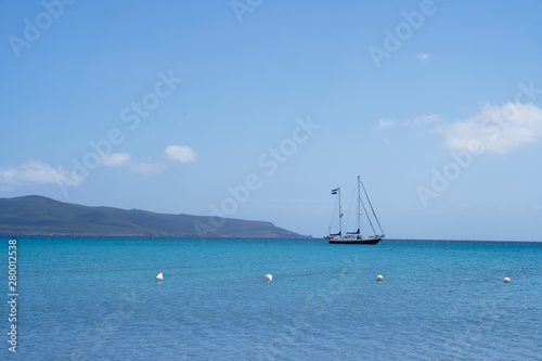 Sailboat at anchor on the sea at a beautiful beach with clear blue sky and turquoise blue water