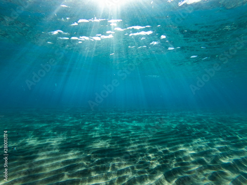 Underwater view of the rocks, sand and stones. The sandy and rocky bottom of the sea with some sun rays.