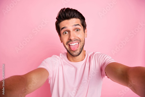 Self-portrait of his he nice attractive lovely cheerful cheery crazy funky guy spending free time fooling having fun isolated over pink pastel background © deagreez