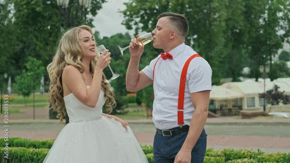 Groom with bride drink champagne outdoors. Wedding couple. Happy family. Man and woman in love. Medium shot of bride and groom having champagne at wedding Groom with bride drink champagne outdoors. Wedding couple. Happy family. Man and woman in love. Medium shot of bride and groom having champagne at wedding