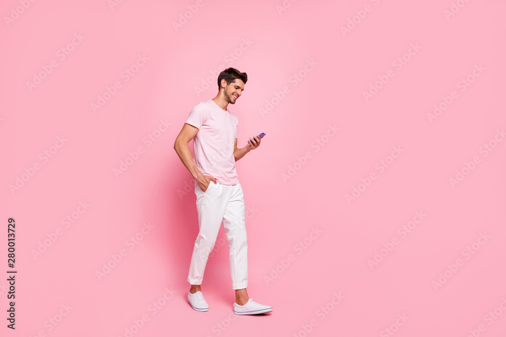 Full length body size view portrait of his he nice attractive content cheerful cheery guy walking enjoying free spare time isolated over pink pastel background Full length body size view portrait of his he nice attractive content cheerful cheery guy walking enjoying free spare time isolated over pink pastel background