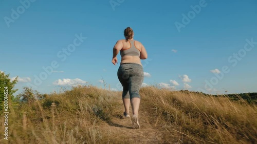 Overweight girl runs up the hill photo