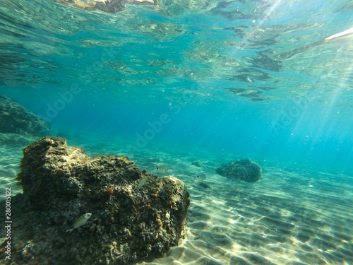 Underwater view of the rocks  sand and stones. The sandy and rocky bottom of the sea with some sun rays.