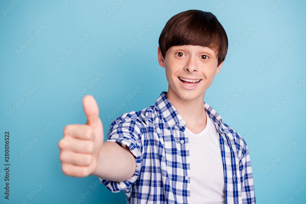 Portarit of pretty boy looking showing like sign smiling dressed in checked shirt isolated over blue background Portarit of pretty boy looking showing like sign smiling dressed in checked shirt isolated over blue background